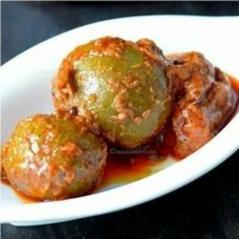 Green olives in a red sauce on a white plate