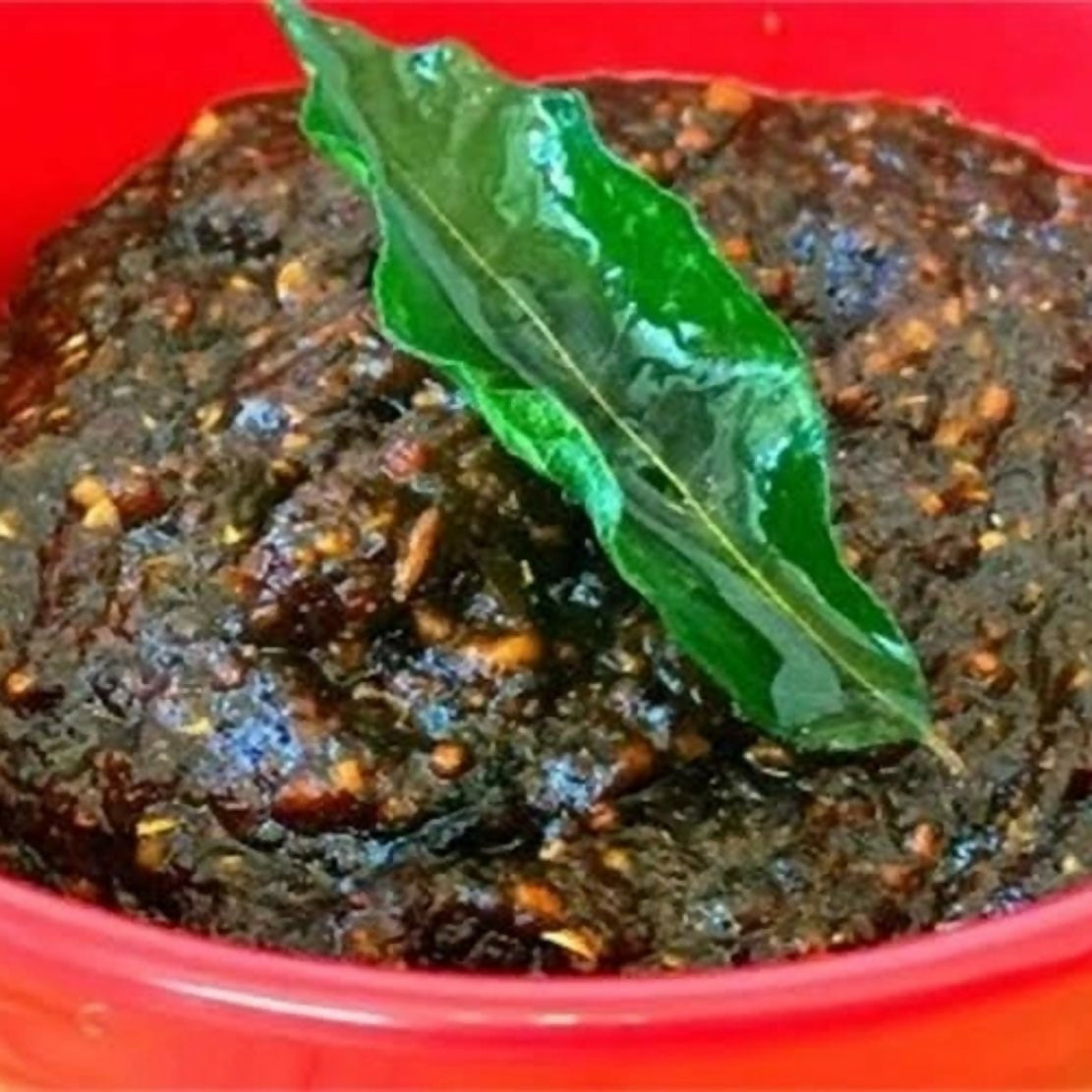 Dark brown paste with a green leaf on a red background