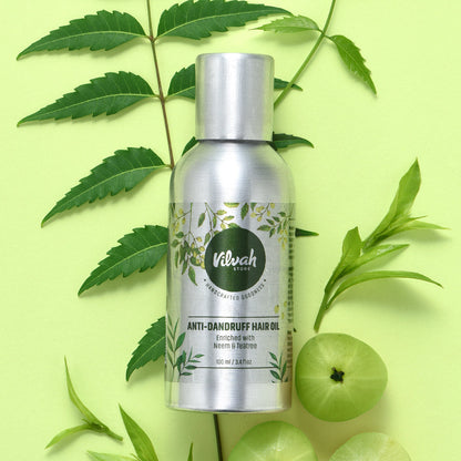 Vilvah Anti-Dandruff Hair Oil bottle with green leaves and fruits on a light green background