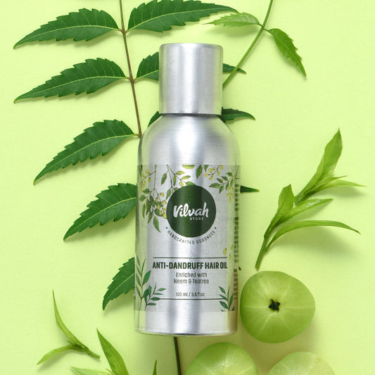 Vilvah Anti-Dandruff Hair Oil bottle with green leaves and fruits on a light green background