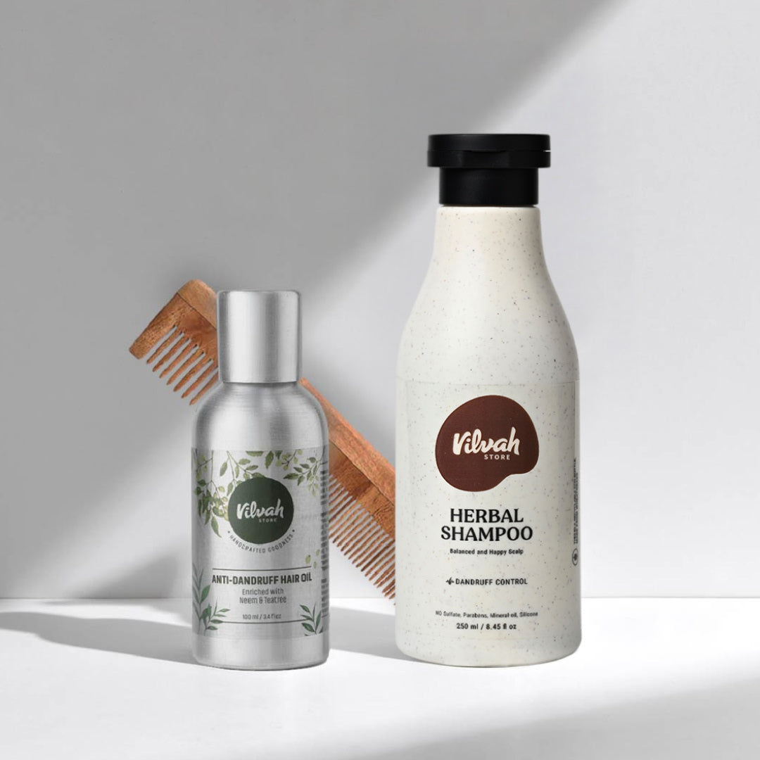 Vilvah hair care products including a bottle of shampoo, a bottle of hair oil, and a wooden comb on a light gray background.