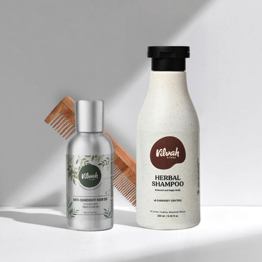 Vilvah hair care products including a bottle of shampoo, a bottle of hair oil, and a wooden comb on a light gray background.