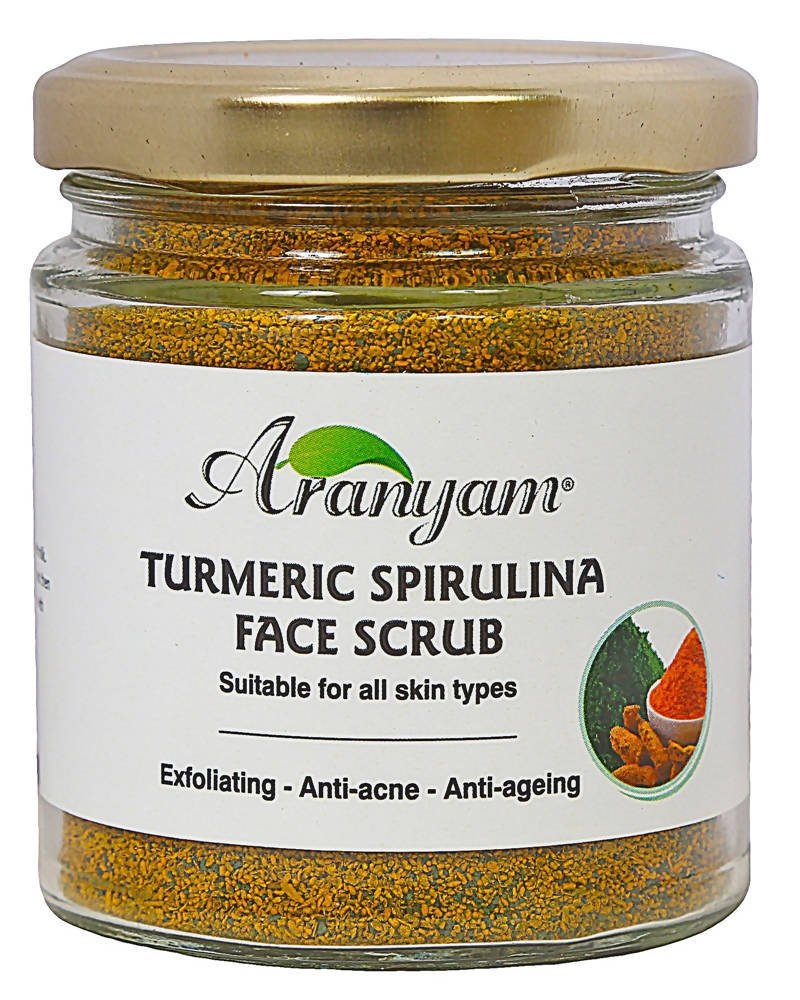 A clear glass jar containing Aranyam Turmeric Spirulina Face Scrub with a label that includes the product name and benefits such as exfoliating, anti-acne, and anti-aging.
