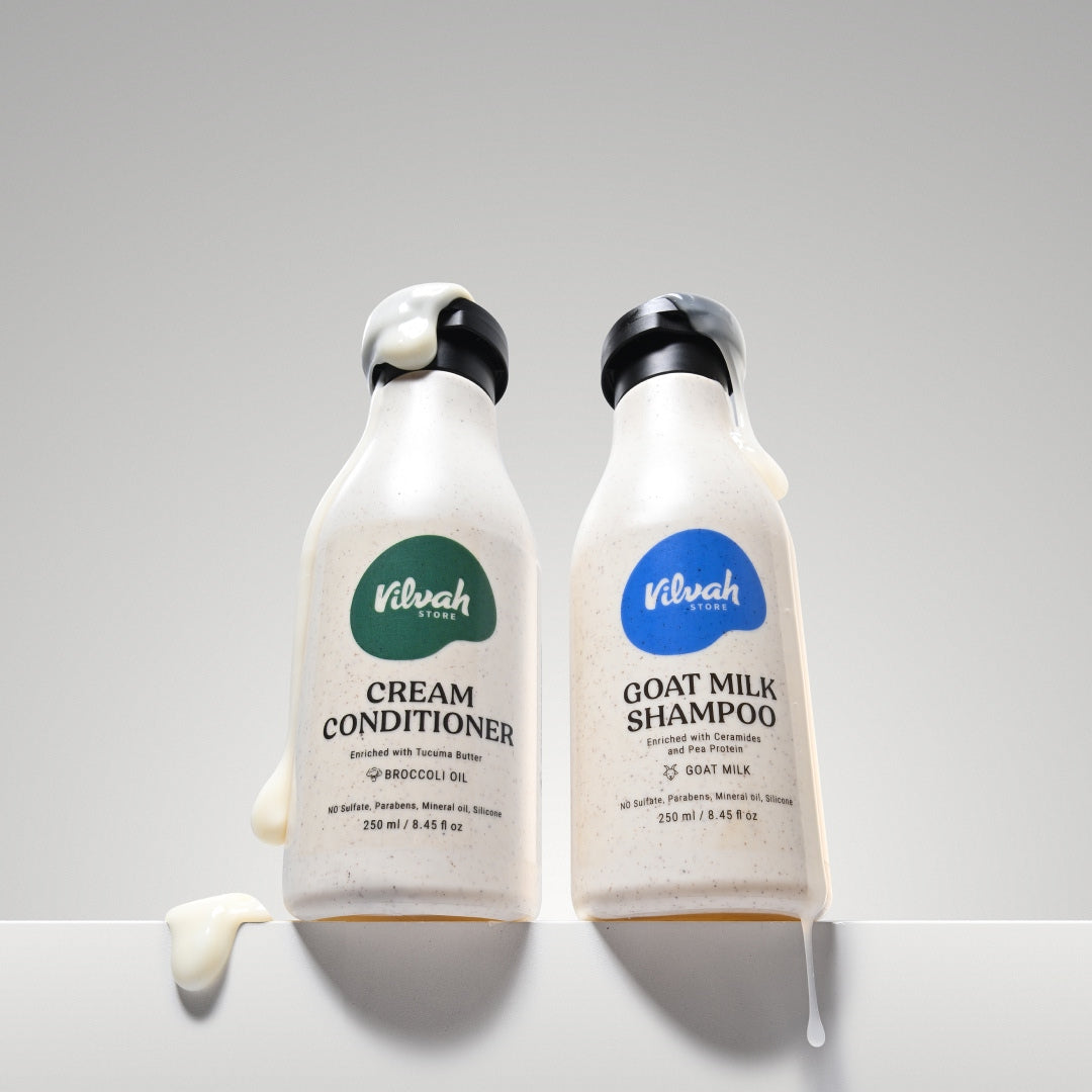 Two bottles of Vilvah Cream Conditioner and Goat Milk Shampoo on a gray background