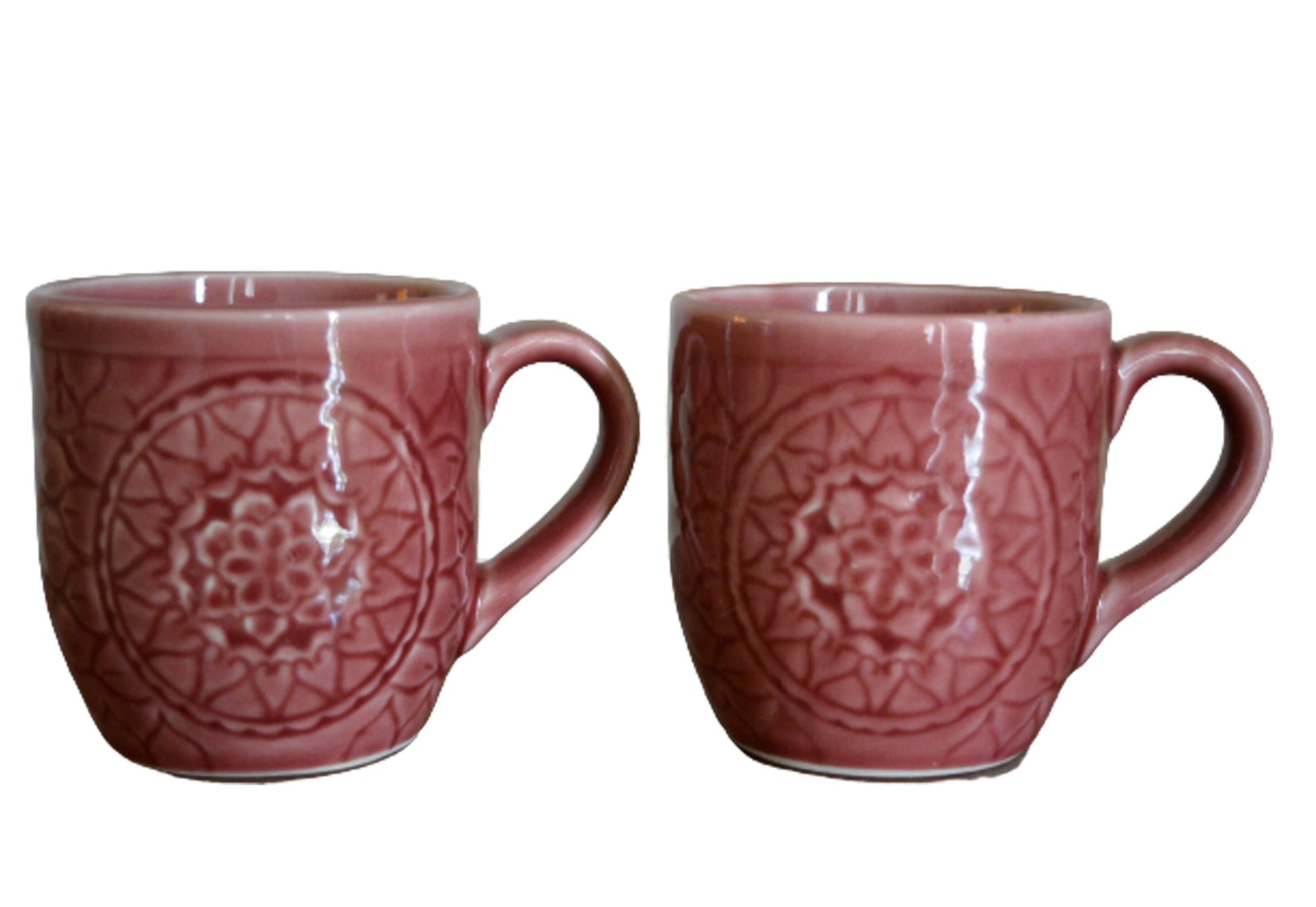 Two red ceramic mugs with decorative patterns on a white background