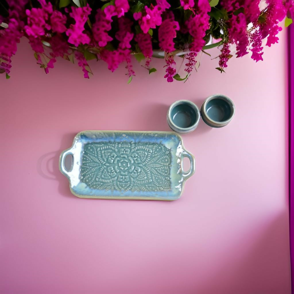 Ceramic tray and bowls on a pink background with pink flowers at the top.