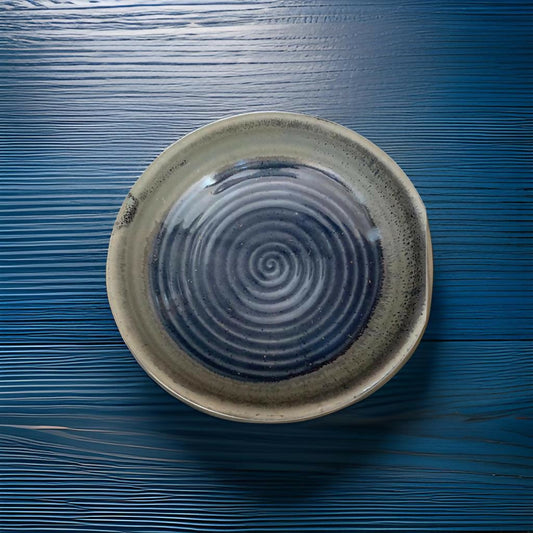 Ceramic plate with spiral design on a blue wooden surface