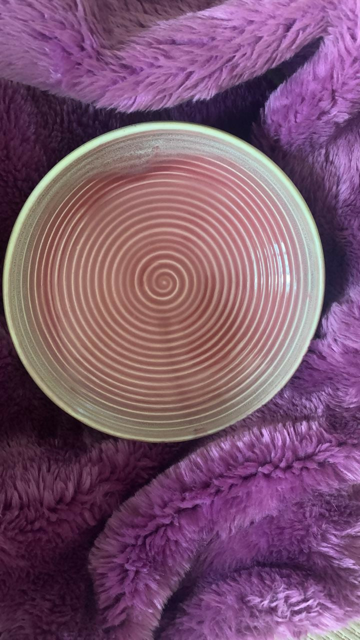 Round pink object with concentric circles on a purple textured surface