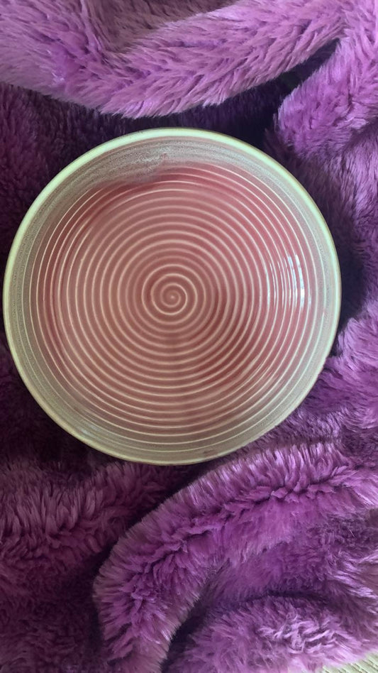 Round pink object with concentric circles on a purple textured surface