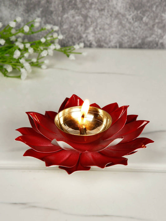 Red lotus-shaped candle holder with a lit candle on a white surface.