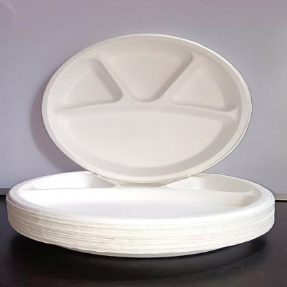 Stack of white disposable plates with compartments on a dark surface.