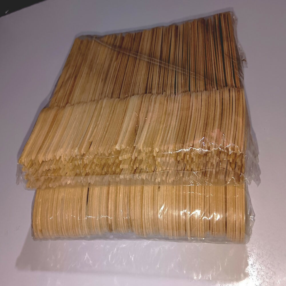 Stack of wooden skewers in clear plastic packaging on a white background