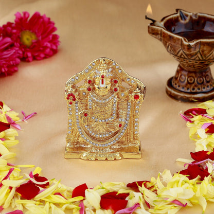 Decorative gold idol with flowers and a lamp on a beige background