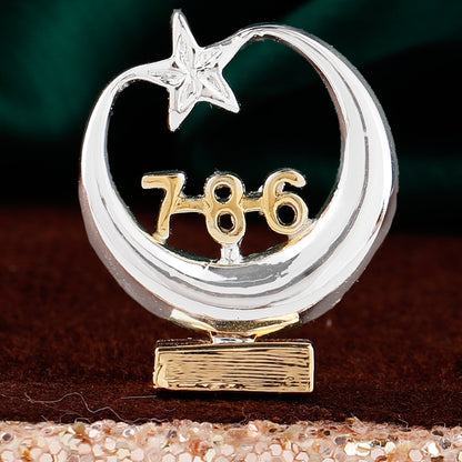 Decorative item with a silver crescent moon and star, gold number '786', and textured base on a dark background.
