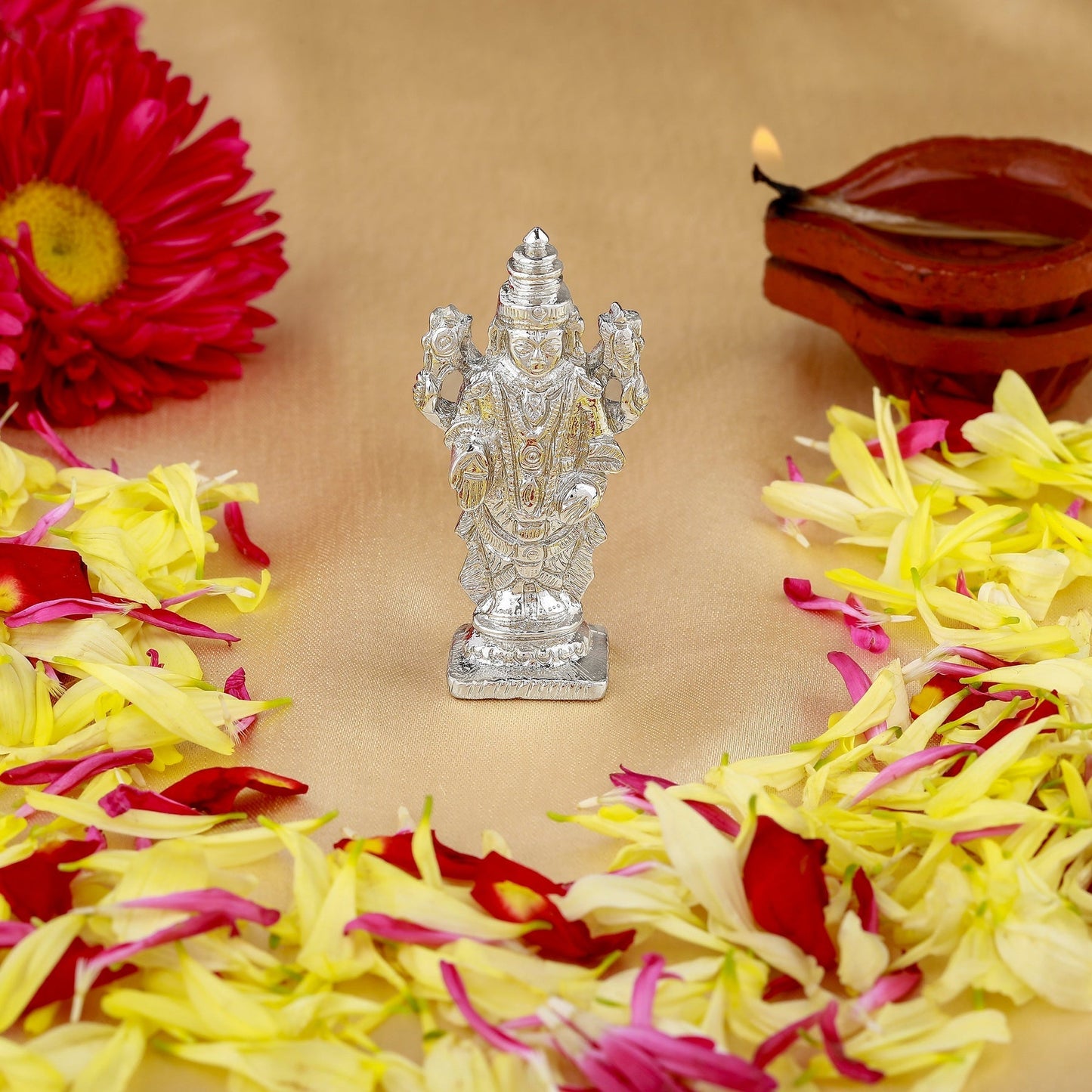 Silver神像 with flowers and a candle on a beige background