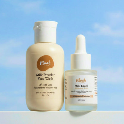 Two skincare products, Milk Powder Face Wash and Milk Drops, by Vilvah against a blue sky background.