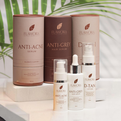 Flawora skincare products including serum, hair serum, lotion, and dropper on a white surface with green leaves in the background.