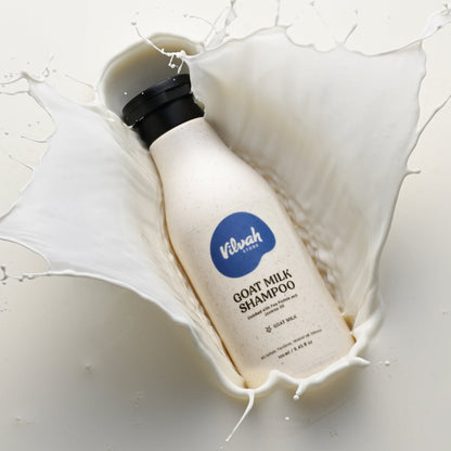 Bottle of Vilshofen Goat Milk Shampoo surrounded by milk splashes on a white background