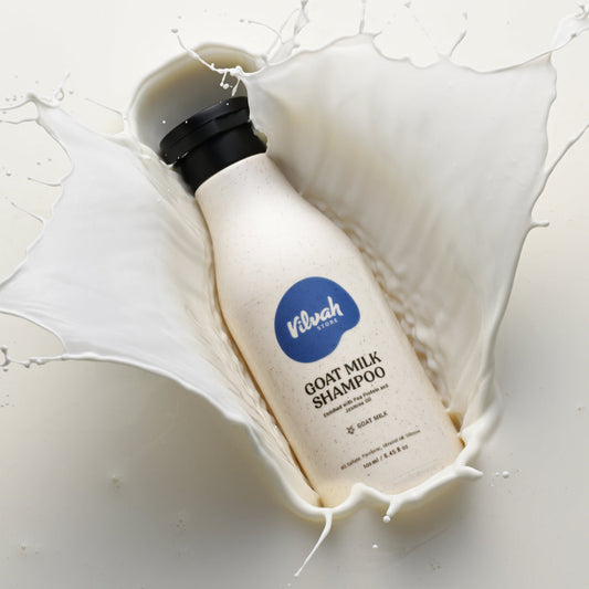 Bottle of Vilshofen Goat Milk Shampoo surrounded by milk splashes on a white background