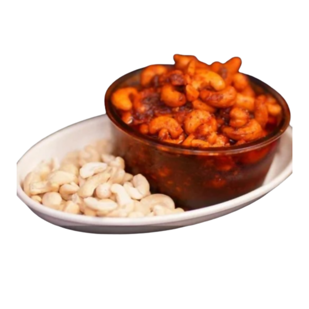 Bowl of cashews with a side of raw cashews on a white plate