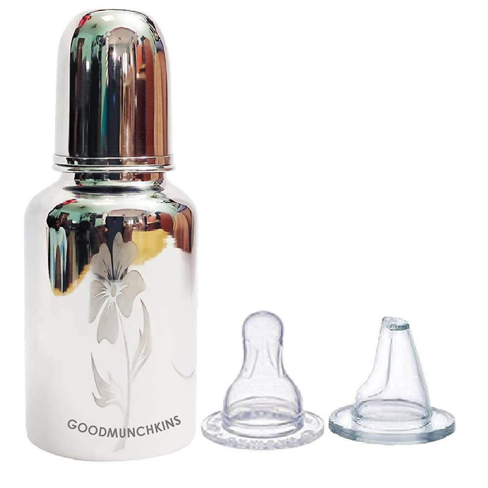 Glass baby bottle with silver cap and two clear nipples on a white background
