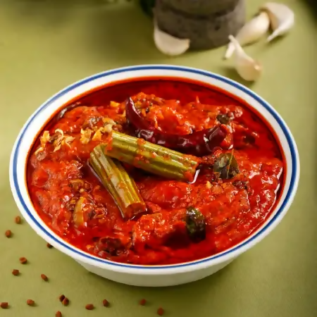 Bowl of spicy red soup with vegetables on a green background