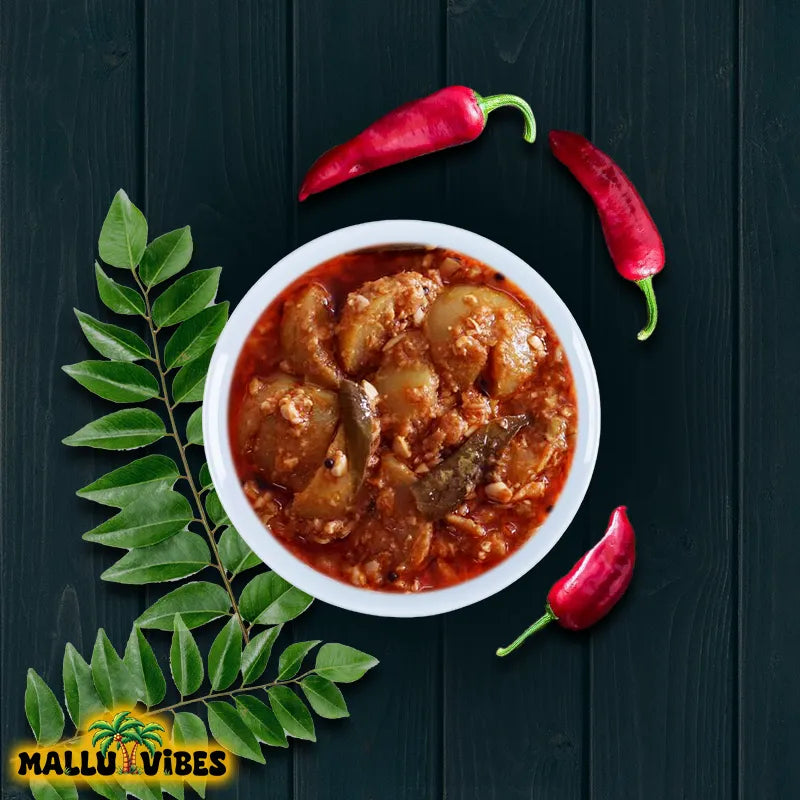 Bowl of curry with red peppers and a leaf on a dark wooden background, featuring the 'Mallu Vibes' logo.