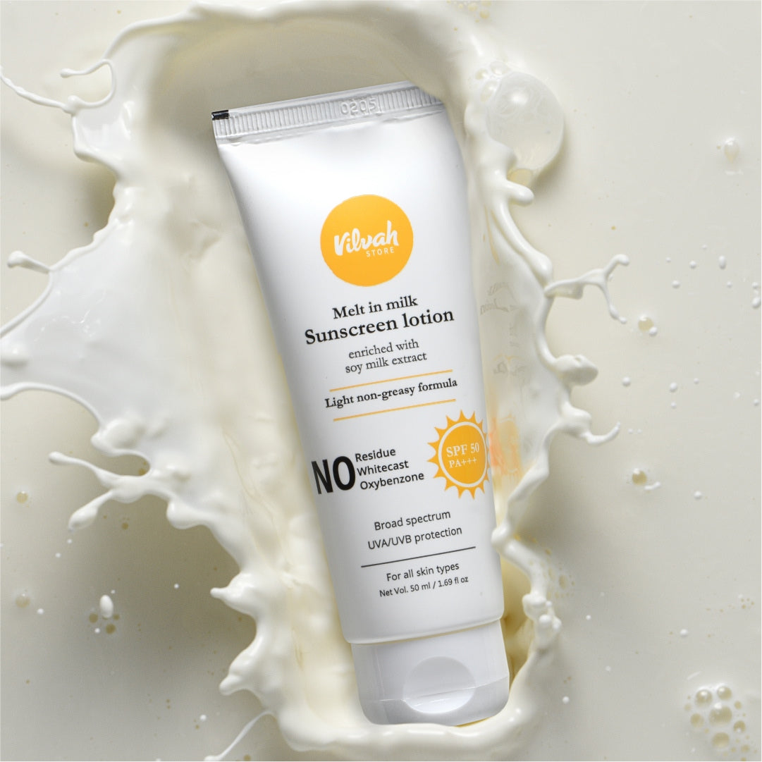 Sunscreen lotion tube with milk splashes on a light background