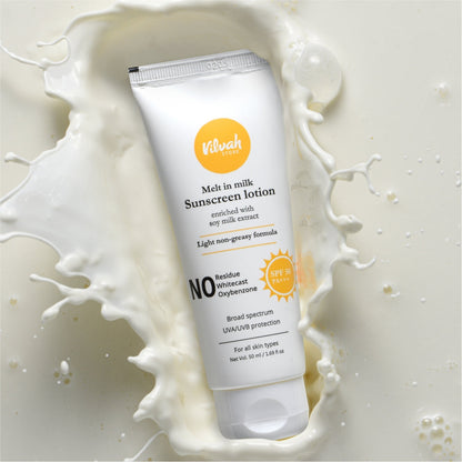 Sunscreen lotion tube with milk splashes on a light background