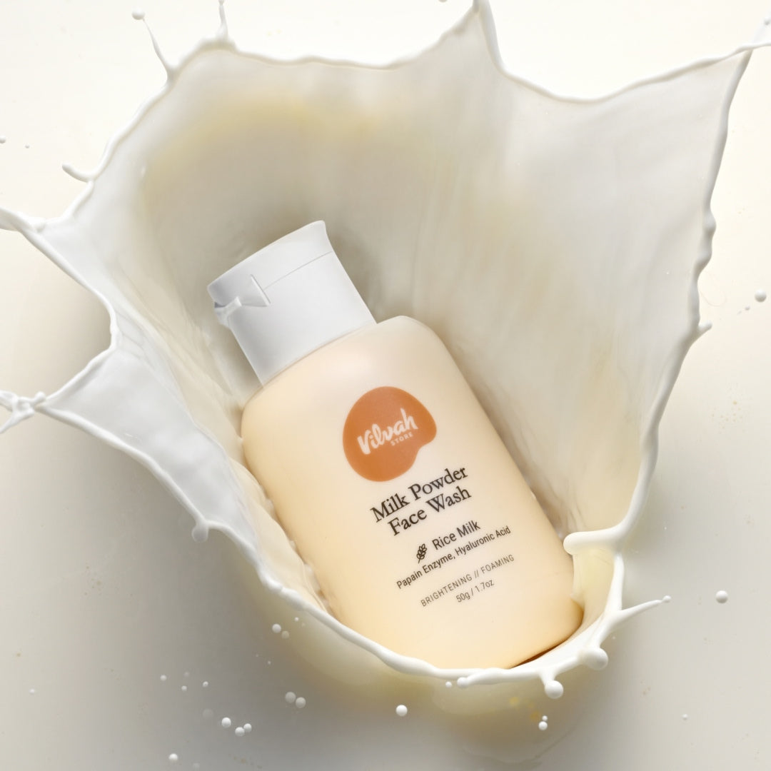 Kibach Milk Powder Face Wash bottle surrounded by splashing milk on a white background