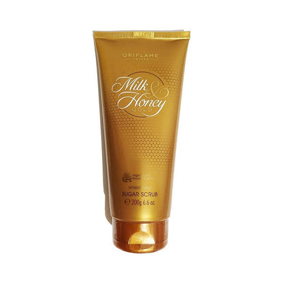 A gold-colored tube of Oriflame Milk & Honey Gold Smoothing Sugar Scrub with elegant text and detailing.