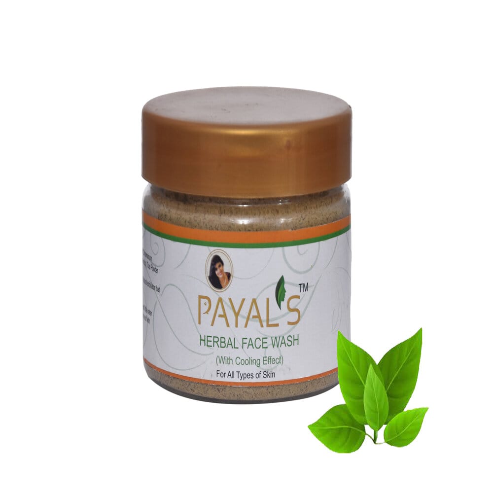 A jar of Payal's Herbal Face Wash with a gold-colored lid, labeled for anti-aging benefits, alongside fresh green leaves.