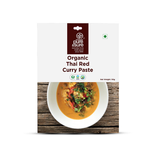Packaging of Organic Thai Red Curry Paste with a bowl of curry on a wooden surface