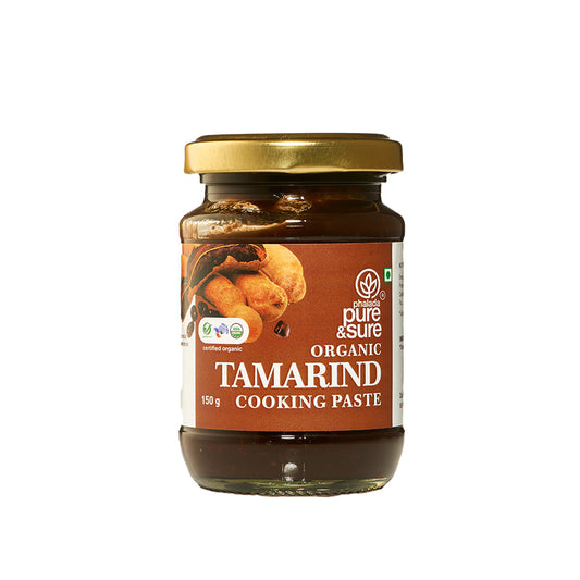 Jar of organic tamarind cooking paste with a gold lid on a white background