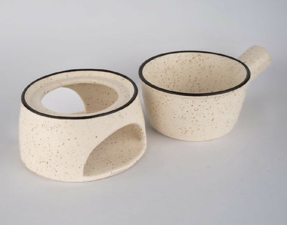 Speckled ceramic bowl and spoon rest on a light gray background