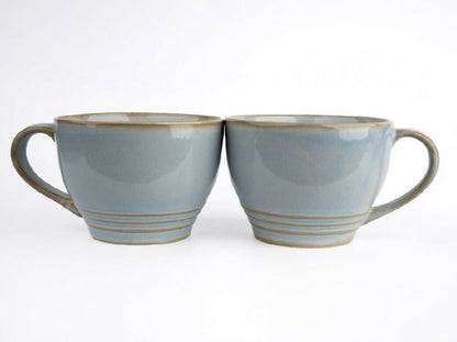 Two gray ceramic mugs with brown accents on a white background