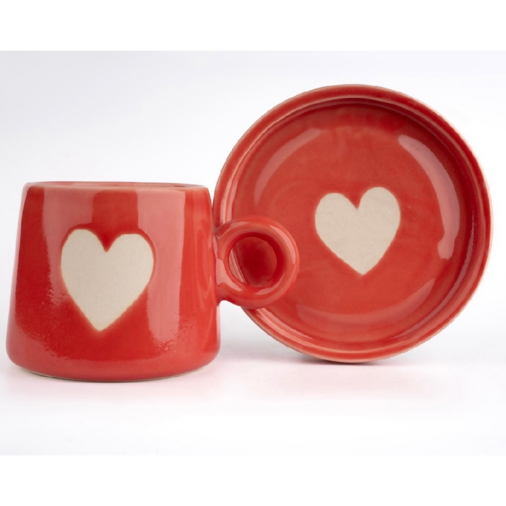 Red ceramic mug and matching bowl with heart designs on a white background