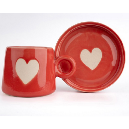 Red ceramic mug and matching bowl with heart designs on a white background