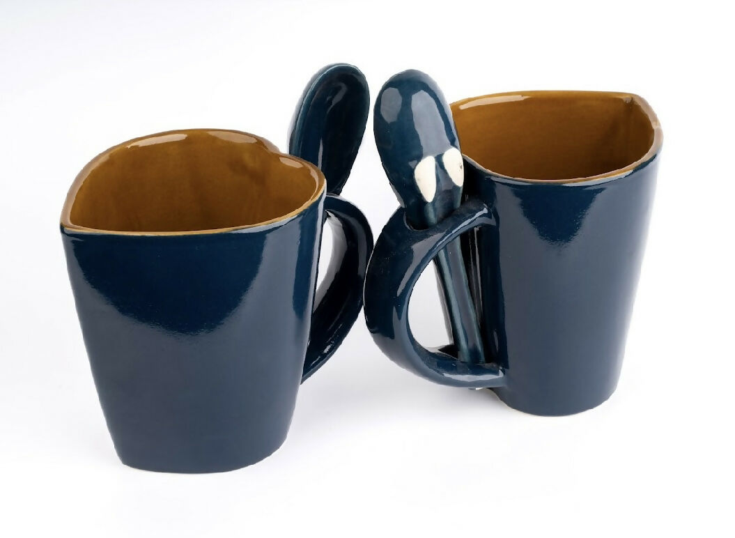 Two navy blue mugs with brown interior on a white background