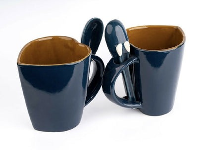 Two navy blue mugs with brown interior on a white background