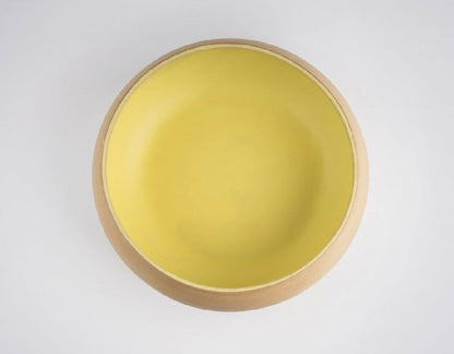 Yellow bowl with wooden rim on a white background