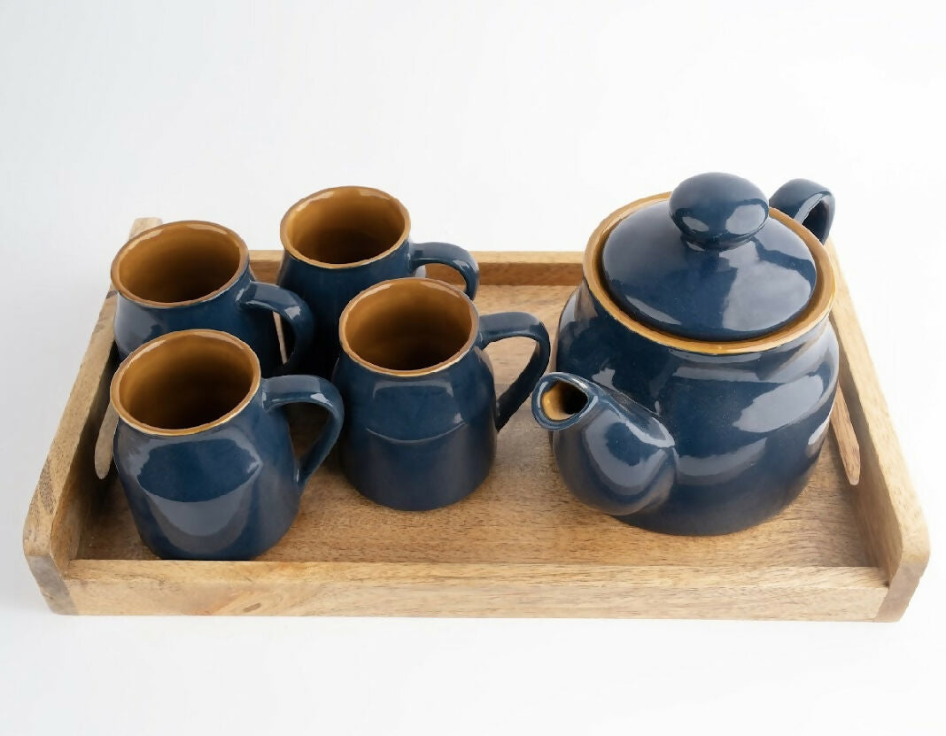 Set of blue ceramic tea pots and mugs on a wooden tray with a white background