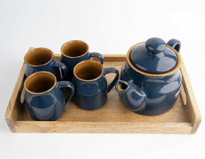 Set of blue ceramic tea pots and mugs on a wooden tray with a white background