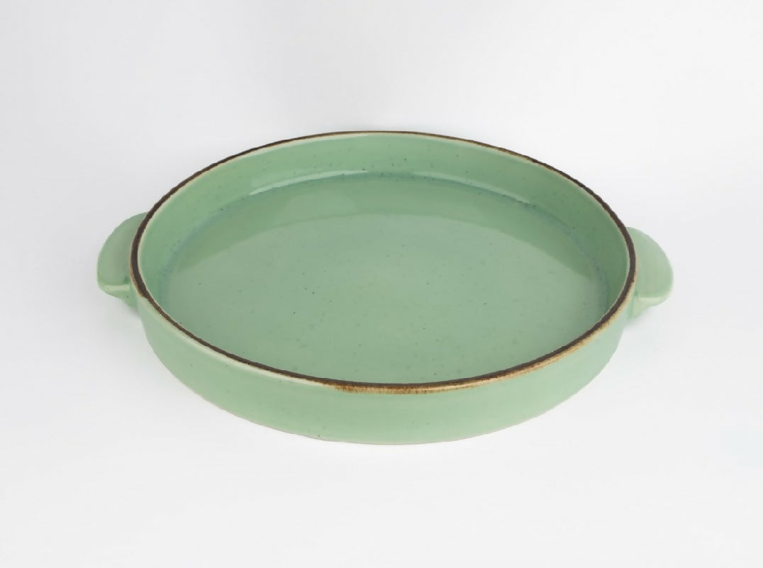 Green ceramic dish with handles on a white background