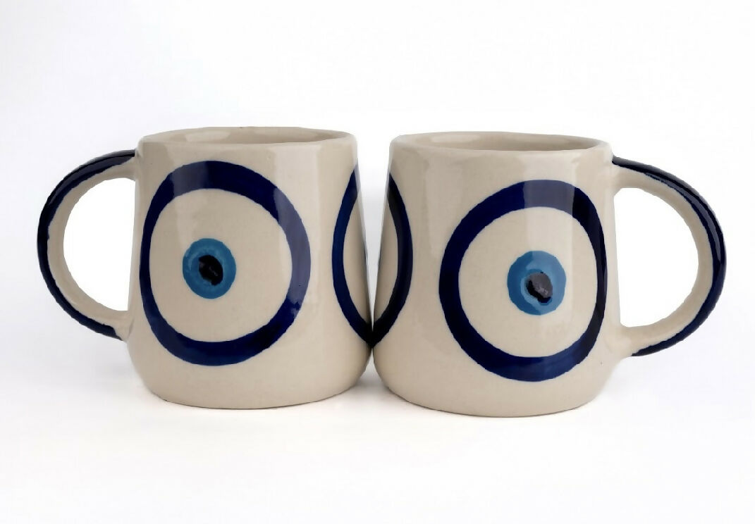 Two ceramic mugs with blue eye design on a white background
