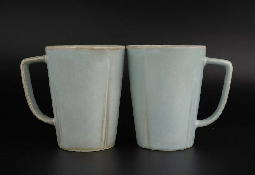 Two ceramic mugs with handles on a black background
