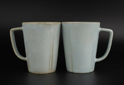 Two ceramic mugs with handles on a black background