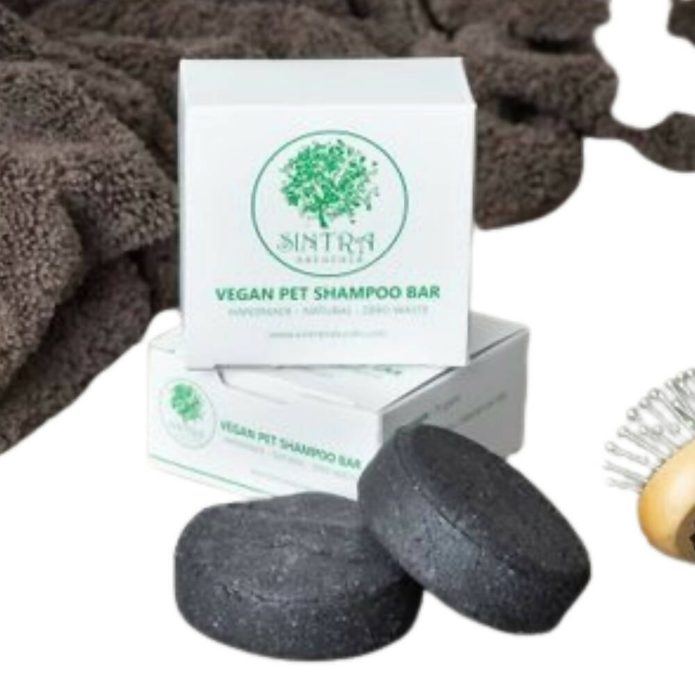 Vegan pet shampoo bar with packaging, a brush, and brown towels on a white background