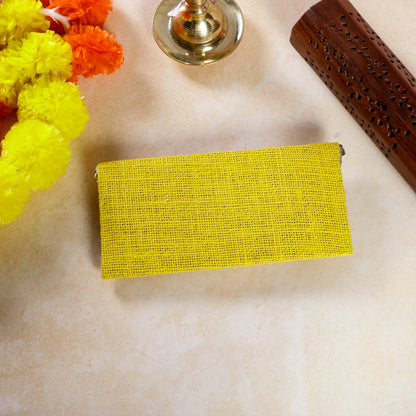Yellow rectangular clutch on a beige surface with decorative elements.