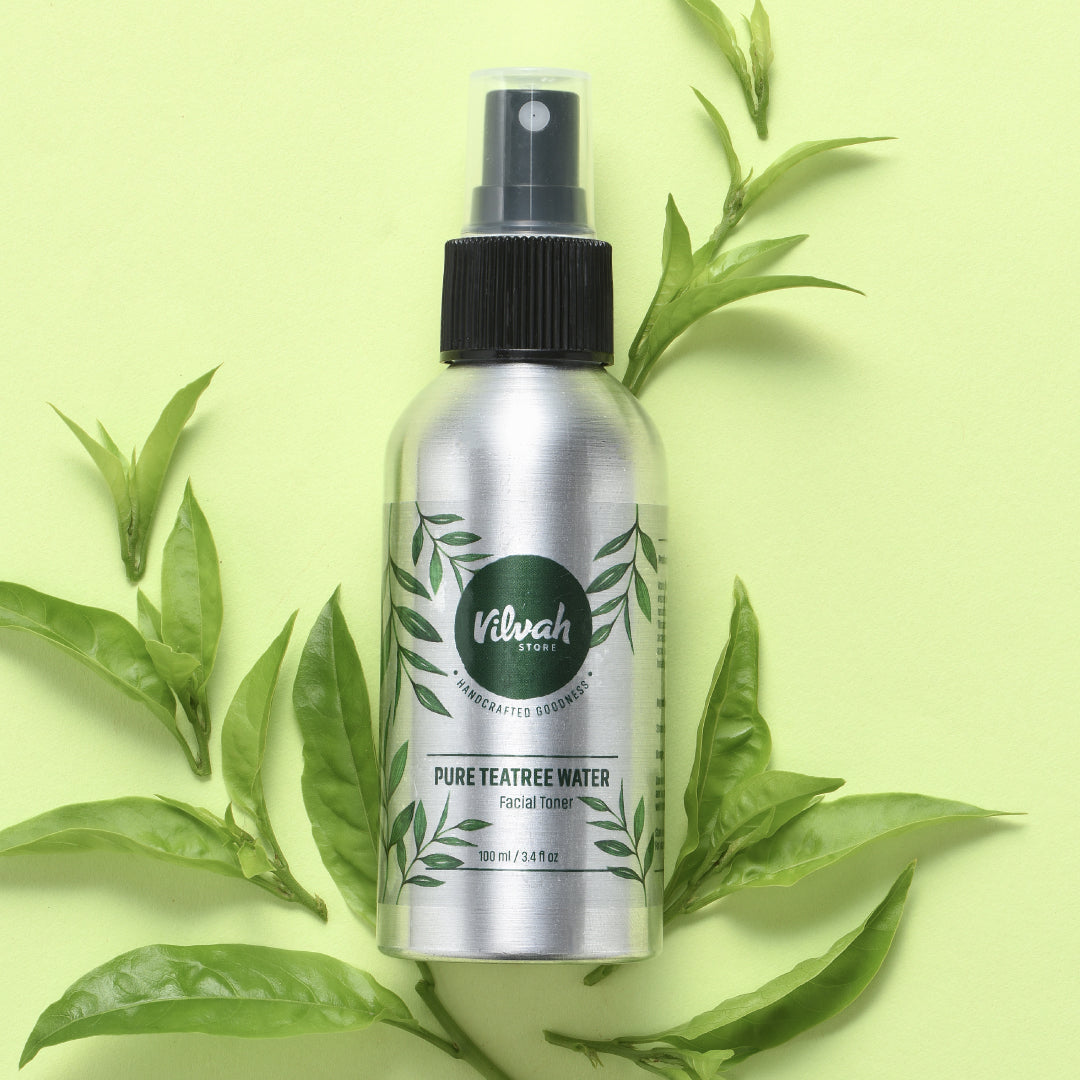 Silver bottle of Viluh Store Pure Teatree Water with black spray nozzle on a light green background with tea leaves.